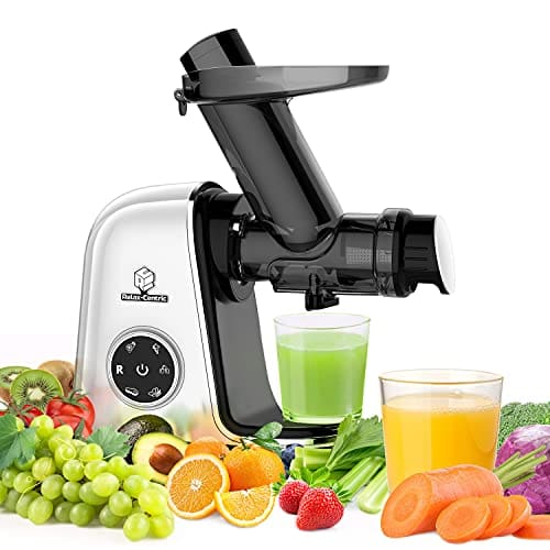 A juicer next to some fruits and vegetables